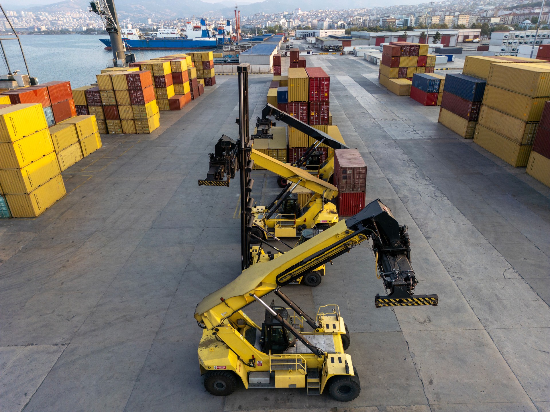 Aerial view of containers in the port being transported by crane.